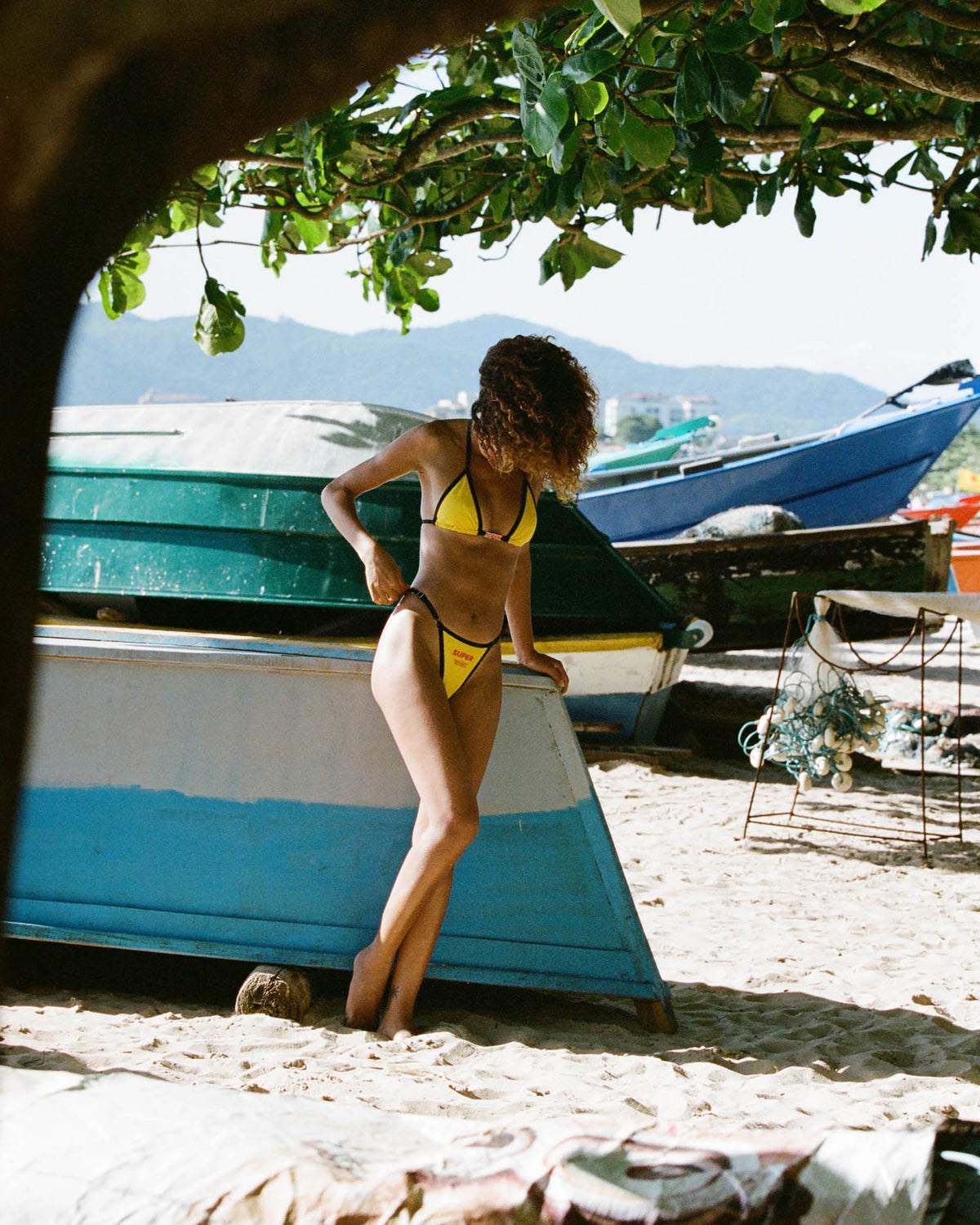 A model radiates sophistication in a mid-rise triangle-style yellow bikini adorned with a sleek black outline on the top. With its timeless design and adjustable sides, this swimwear captures a chic and classic essence for a standout summer bikini look.