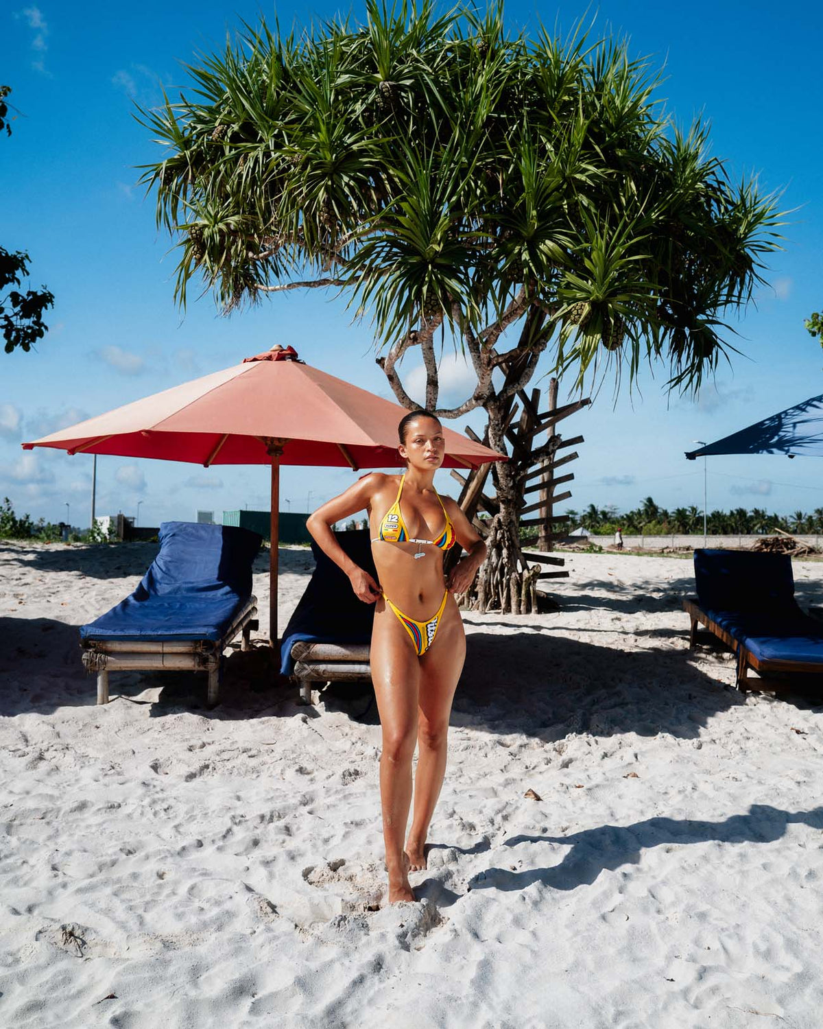 Yellow Pitstop Group B triangle thong bikini with colourful racing graphics & charm bar, front view on model.
