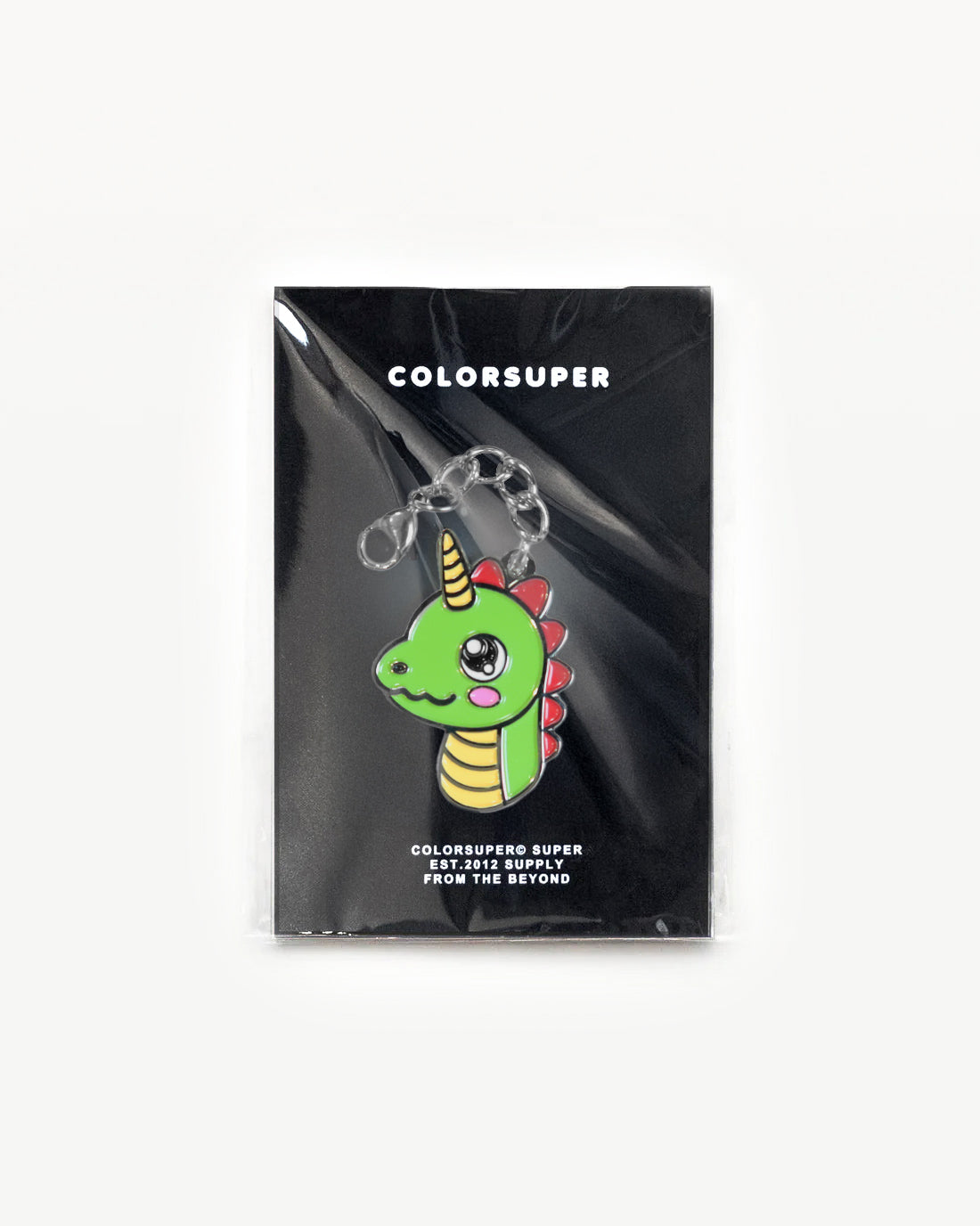 Bright green Cute Dino charm with a gold horn on a black packaging background. - Alternate view